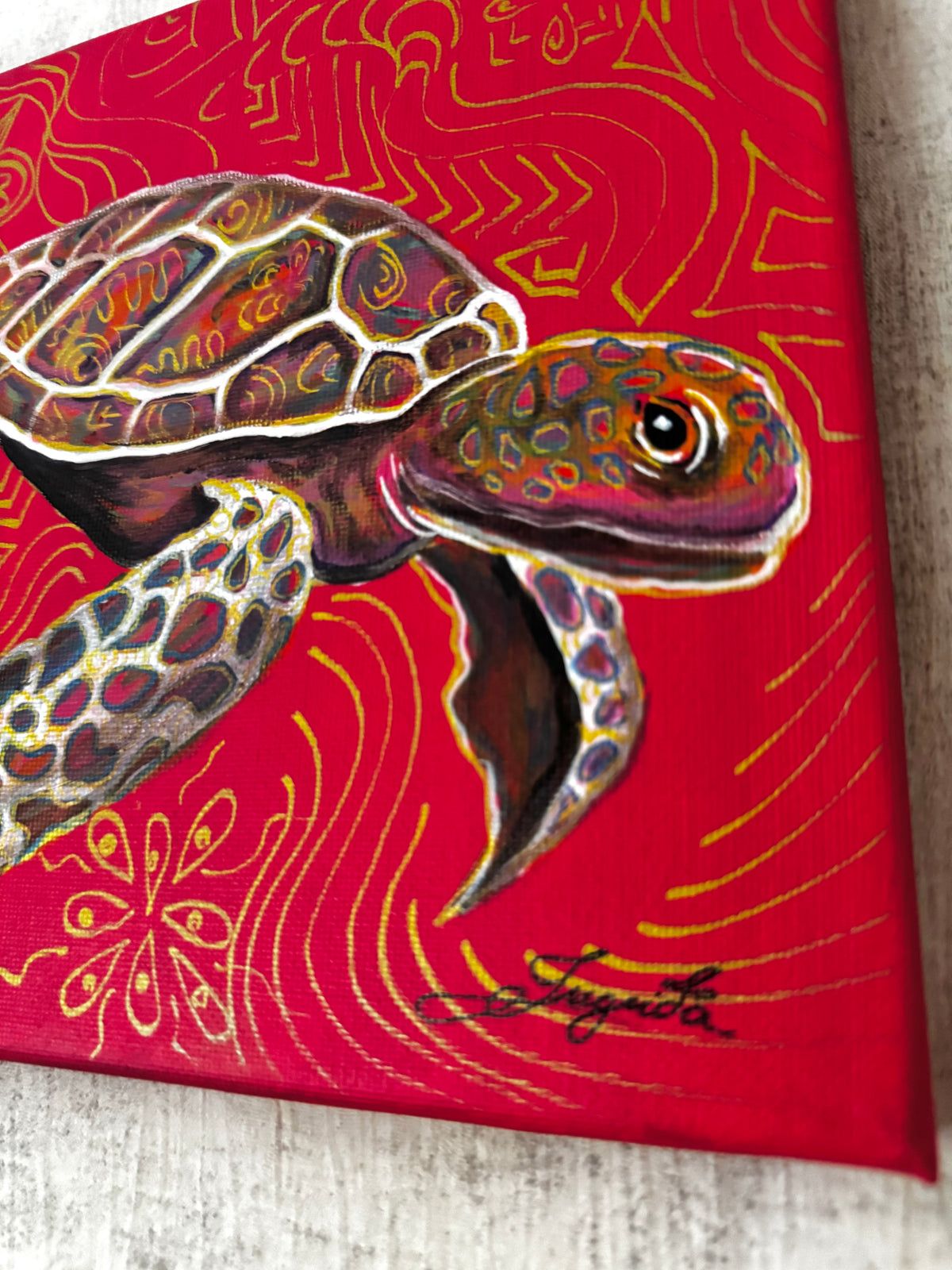 A-close-up-of-a-canvas-wall-art-print-featuring-a-painted-sea-turtle-on-a-bright-red-background-with-gold-abstract-wave-and-floral-patterns-artist-signature-ingrida-art-golden-symbols